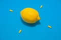 One yellow lemon and four pills on blue background Royalty Free Stock Photo