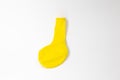 One bright yellow inflatable uninflated colored balloon for the holiday lies on a white background Royalty Free Stock Photo