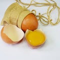 one broken chicken egg and one whole in a bag, shell and yolk on a light background close-up Royalty Free Stock Photo