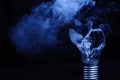 One broken light bulb on a blue background with smoke. Overdue idea concept