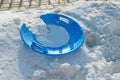 One broken round blue plastic sled plate lies on a snowdrift Royalty Free Stock Photo