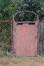 one brown closed old iron door on a fence made of metal mesh Royalty Free Stock Photo