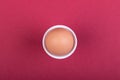 one brown egg in white egg cup before red background, photo from above Royalty Free Stock Photo