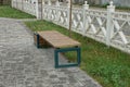 One brown empty wooden bench stands on a gray paving slab by an alley with green grass Royalty Free Stock Photo