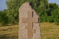 One brown granite monument with a cross stands on a grave
