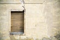 One brown grungy yellow wooden window in a gray yellow broken cracked facade of an abandoned derelict house Royalty Free Stock Photo