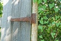 One brown iron door hinge on a metal pipe and a gray wooden door board Royalty Free Stock Photo