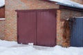 Brown iron gate on the wall of an old garage outside in white snow Royalty Free Stock Photo