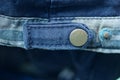 One brown metal button rivet on a blue cotton harness