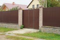 One brown metal gate and part of a fence