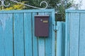 One brown metal mailbox hanging on a blue wooden fence Royalty Free Stock Photo
