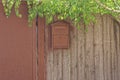 One brown metal mailbox hanging on a gray wooden fence wall Royalty Free Stock Photo
