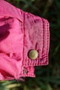 One brown metal rivet button on the pink fabric sleeve