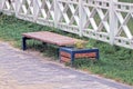 One brown wooden bench stands on a gray paving slab by an alley Royalty Free Stock Photo