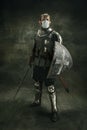 One brutal bearded man, medeival warrior or knight in medical mask with shield and sword over dark background. Royalty Free Stock Photo