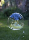Large soap bubble floating against a blurred background with bubble popping Royalty Free Stock Photo