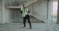 One builder dancing funny in the construction site wearing a hard hat and high visibility vest