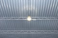 One bulb hanging from the ceiling under a metal lattice in a large industrial warehouse.