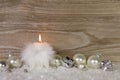 One burning candle with white feathers and snow and silver decor