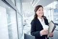 One businesswoman holding a takeaway, reusable cup of coffee and folder of paperwork in the office. Smiling corporate Royalty Free Stock Photo