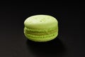 One cake of macaroni green color. Delicious pistachio macaroon isolated on black background. French sweet cookie