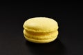 One cake of macaroni yellow lemon color. Delicious macaroon isolated on black background. French sweet cookie Royalty Free Stock Photo