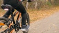 One caucasian children rides bike road in autumn park. Little girl riding black orange cycle in forest. Kid goes do Royalty Free Stock Photo