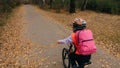 One caucasian children rides bike road in autumn park. Little girl riding black orange cycle in forest. Kid goes do Royalty Free Stock Photo