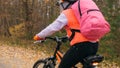 One caucasian children rides bike road in autumn park. Little girl riding black orange cycle in forest. Kid goes do bicycle sports Royalty Free Stock Photo