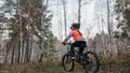 One caucasian children rides bike road in autumn park. Little girl riding black orange cycle in forest. Kid goes do Royalty Free Stock Photo