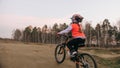 One caucasian children rides bike road track in dirt park. Girl riding black orange cycle in racetrack. Kid goes do Royalty Free Stock Photo