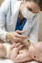 One caucasian female doctor is giving some dose of liquid medicine to infant baby boy by syringe into the mouth from disease or fo Royalty Free Stock Photo