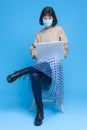 One caucasian Girl Sitting with Laptop And Wearing Facial Surgical Protective Mask Against Viruses Against Blue Background Royalty Free Stock Photo