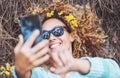 One cheerful beautiful woman taking selfie picture laying down on the ground in forest woods and wearing yellow flowers. People Royalty Free Stock Photo