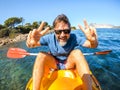 One cheerful man have fun and pose for a crazy picture sitting inside a yellow kayak canoe with ocean water and coast in