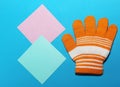 One children`s orange glove with white stripes lies on the blue surface, fingers splayed, the ability to warm your hands in winter