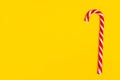 One christmas candy cane on yellow backgroud, copy space