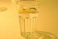 One clear glass full of drink and a piece of lemon