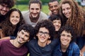 We are one close group of friends. Portrait of a group of young students standing arms around each other outside in a