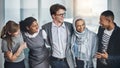 They are one close team. Shot of a group of young cheerful businesspeople standing with arms around inside of the office