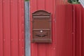 One closed brown mailbox hanging on a red metal wall Royalty Free Stock Photo