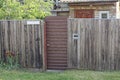 One closed brown metal door on a gray wooden fence Royalty Free Stock Photo