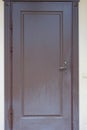 one closed brown metal-plastic door on a gray wall of a house Royalty Free Stock Photo