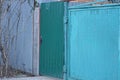 one closed iron door on a gray green metal fence