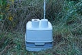 One closed mobile plastic gray dry closet with a roll of white toilet paper