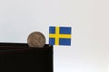 One coin of Swedish Krona money and mini Sweden flag stick on the black wallet with white background Royalty Free Stock Photo