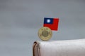 One coin of Taiwan fifty dollars money on reverse and mini Taiwan flag stick on the leather wallet on grey background