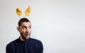 One color creative banner for Easter and place for your text and advertising. Caucasian man with yellow plush rabbit ears sits and