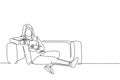 One continuous line drawing of young businesswoman lying down on the sofa while reading book and holding a cup of coffee drink. Royalty Free Stock Photo
