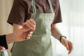 One cook passes a kitchen brush to another cook in a green apron